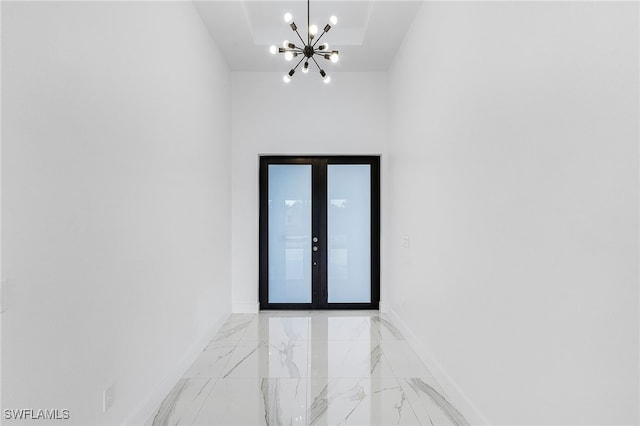 empty room featuring a tray ceiling, french doors, and a chandelier