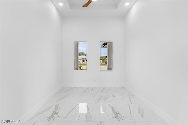 empty room featuring ceiling fan, a raised ceiling, and a towering ceiling