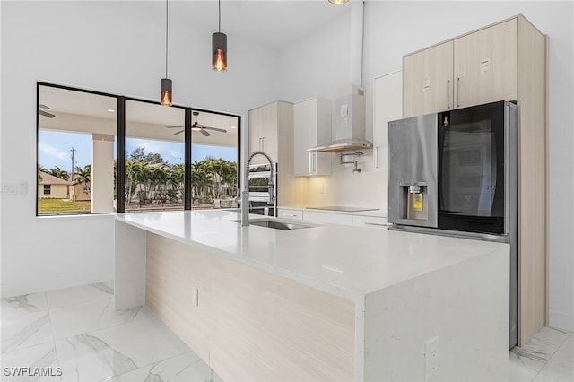 kitchen featuring stainless steel refrigerator with ice dispenser, sink, hanging light fixtures, a kitchen island with sink, and exhaust hood