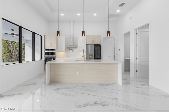 kitchen featuring a towering ceiling, pendant lighting, light brown cabinetry, sink, and stainless steel appliances