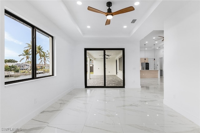 empty room featuring ceiling fan and a raised ceiling