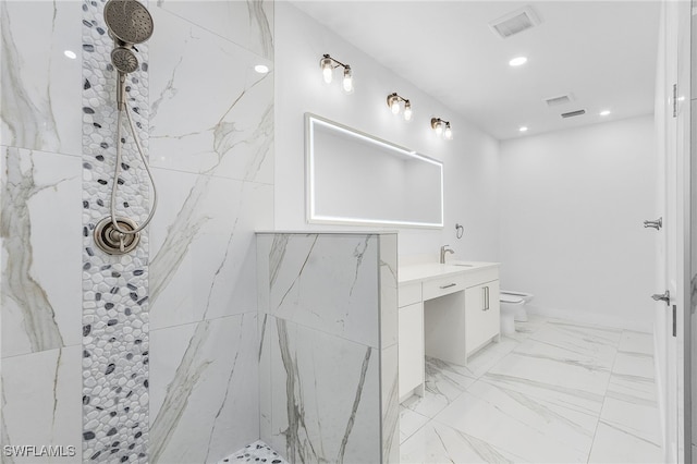 bathroom with vanity, a tile shower, and toilet