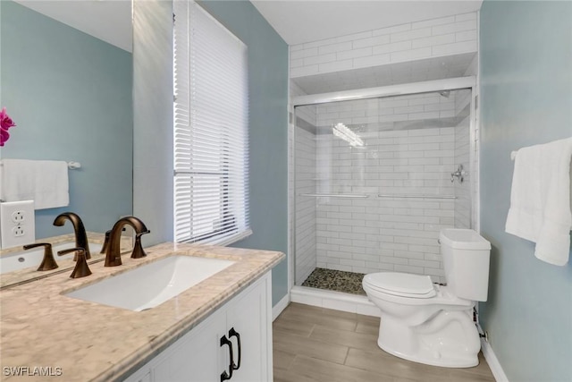 bathroom with a shower with door, vanity, and toilet