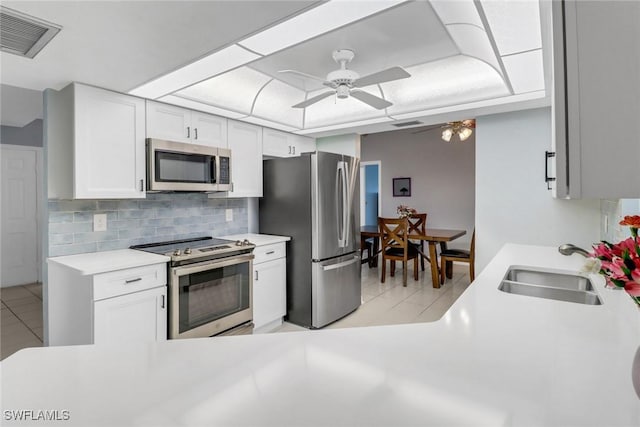 kitchen with sink, white cabinetry, light tile patterned floors, appliances with stainless steel finishes, and backsplash