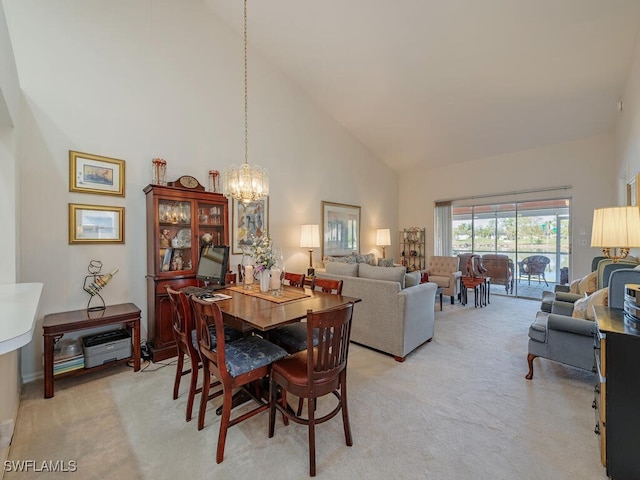 dining area featuring light colored carpet, high vaulted ceiling, and a chandelier