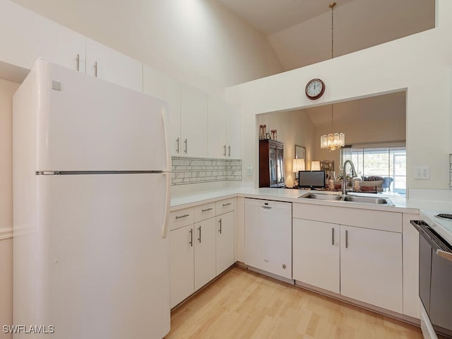 kitchen featuring sink, white appliances, white cabinetry, hanging light fixtures, and vaulted ceiling