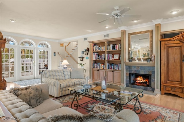 living room featuring crown molding, ceiling fan, wood-type flooring, and a fireplace