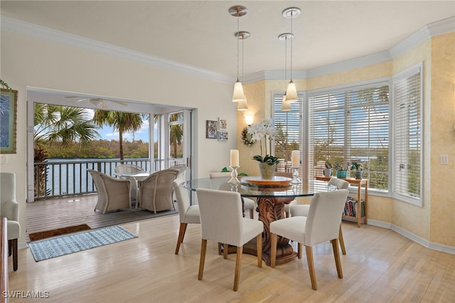 dining area featuring light wood-type flooring, a healthy amount of sunlight, and crown molding