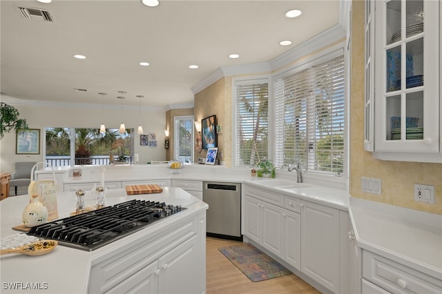 kitchen featuring appliances with stainless steel finishes, sink, white cabinets, hanging light fixtures, and ornamental molding