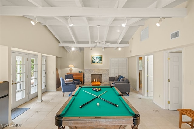 game room with beam ceiling, visible vents, a warm lit fireplace, and track lighting