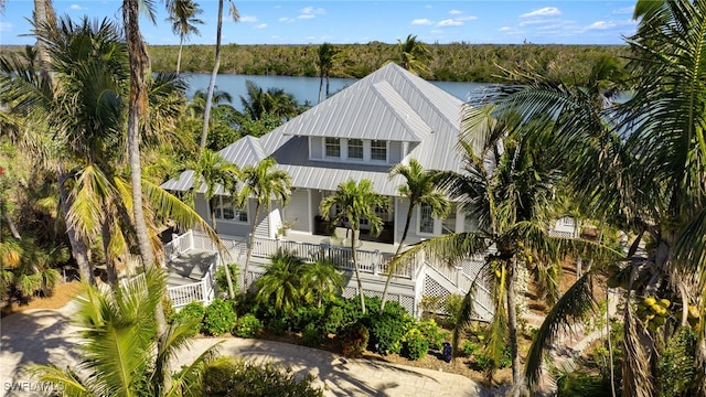 view of front of home featuring a water view, driveway, stairway, covered porch, and metal roof