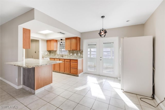 kitchen with backsplash, hanging light fixtures, white fridge, kitchen peninsula, and french doors