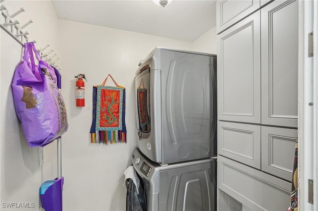 laundry room featuring stacked washer / dryer and cabinets