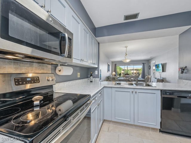 kitchen with sink, light tile patterned floors, appliances with stainless steel finishes, kitchen peninsula, and white cabinets