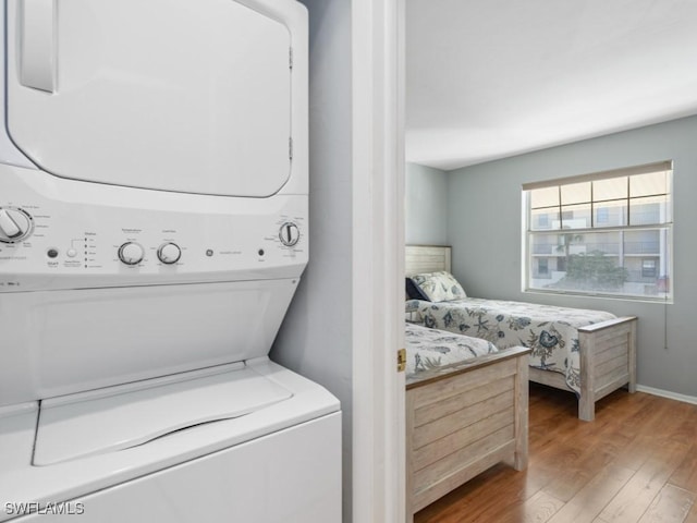 laundry room featuring stacked washer and dryer and hardwood / wood-style flooring