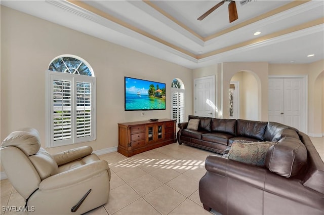 tiled living room with a raised ceiling and ceiling fan