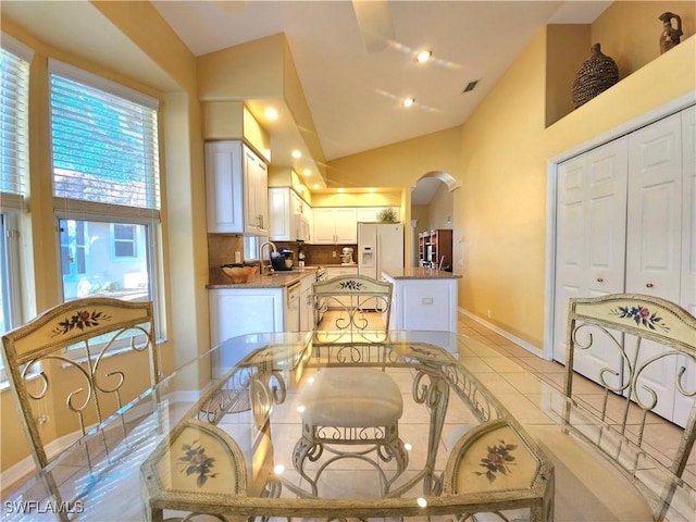 dining area with high vaulted ceiling and light tile patterned flooring