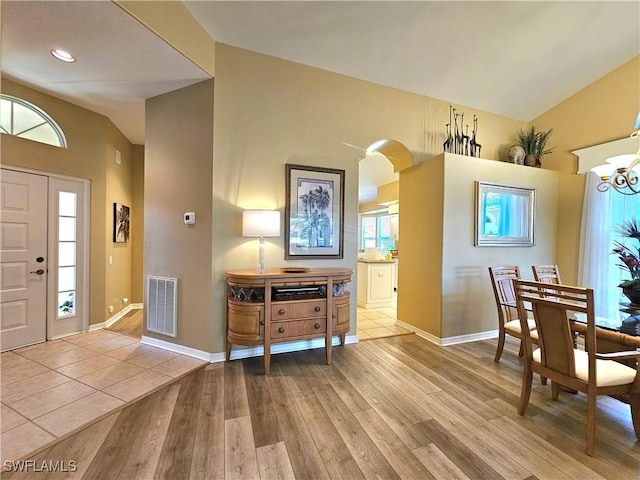 foyer featuring an inviting chandelier, vaulted ceiling, and light hardwood / wood-style flooring