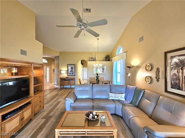 living room featuring ceiling fan with notable chandelier, hardwood / wood-style floors, and high vaulted ceiling