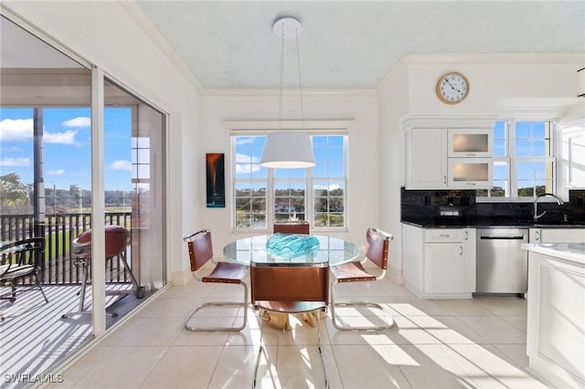 dining room featuring light tile patterned flooring, a healthy amount of sunlight, crown molding, and sink