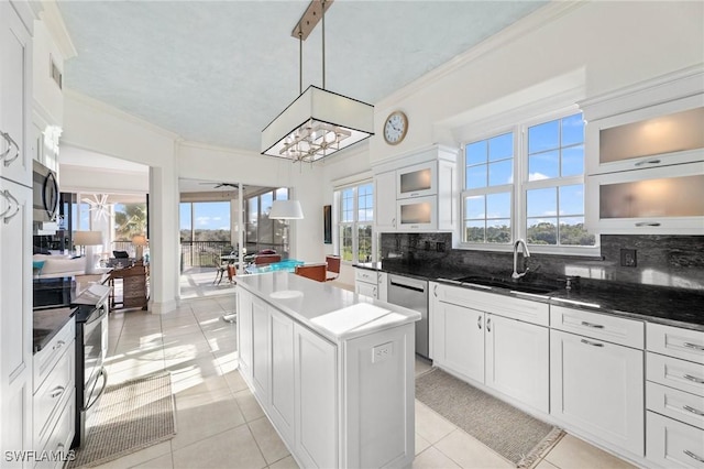 kitchen with sink, appliances with stainless steel finishes, hanging light fixtures, white cabinets, and a kitchen island