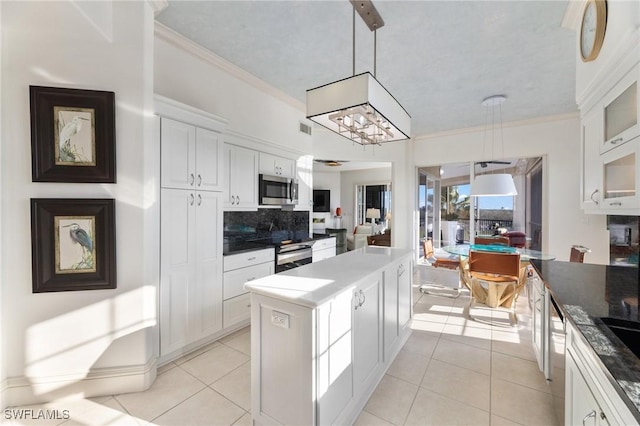 kitchen with crown molding, appliances with stainless steel finishes, hanging light fixtures, and white cabinets