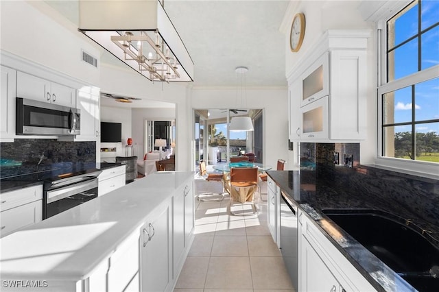 kitchen featuring stainless steel appliances, white cabinetry, sink, and decorative light fixtures