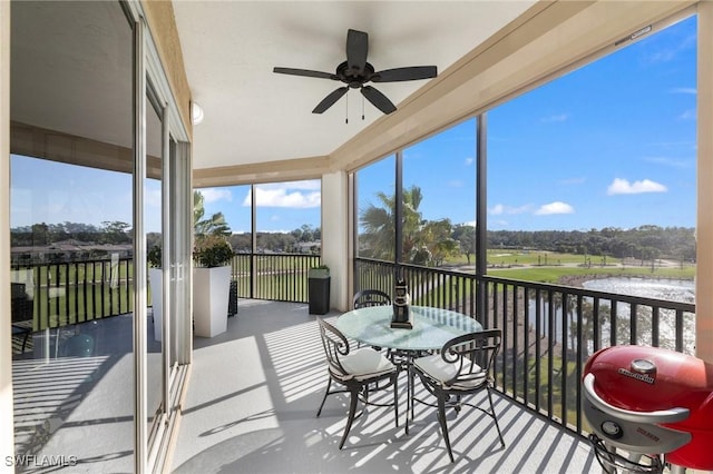 sunroom with a water view and ceiling fan