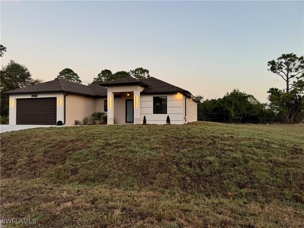 view of front of home with a garage and a lawn