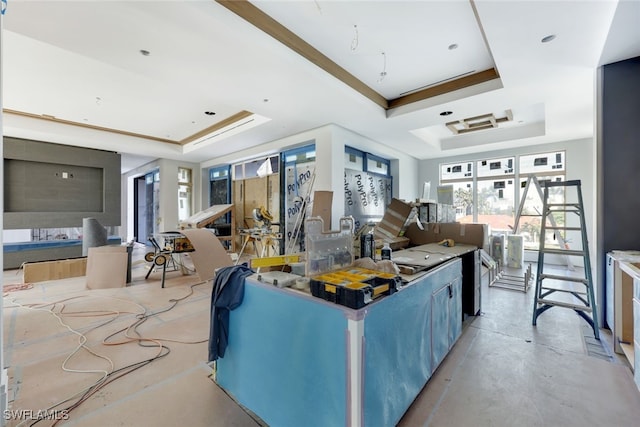 living area with a raised ceiling and concrete floors