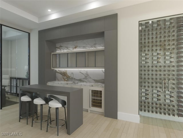 bar with recessed lighting, light wood-style flooring, a sink, beverage cooler, and baseboards