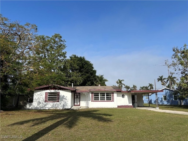 ranch-style house featuring a carport and a front lawn