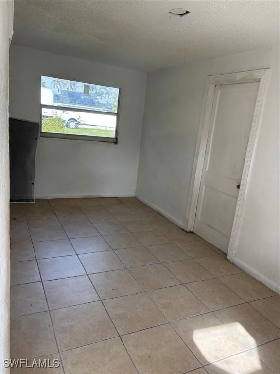 tiled spare room with a textured ceiling