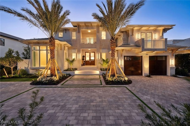 view of front of home with french doors, a balcony, and a garage