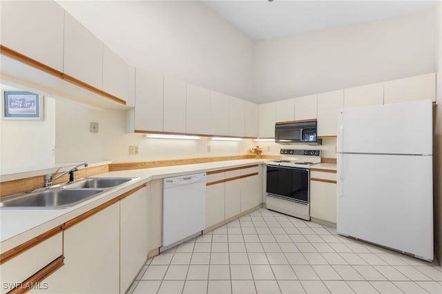 kitchen featuring white appliances, sink, a high ceiling, and white cabinets