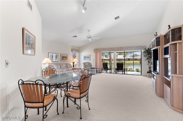 carpeted dining space featuring vaulted ceiling, track lighting, and ceiling fan