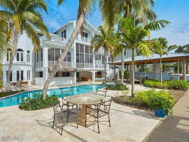 back of house featuring a balcony, a sunroom, and a patio area