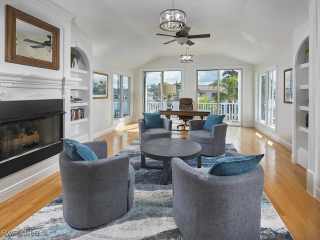 living room featuring ceiling fan, lofted ceiling, light hardwood / wood-style floors, and built in shelves