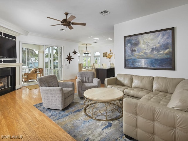 living room with crown molding, ceiling fan with notable chandelier, and hardwood / wood-style floors