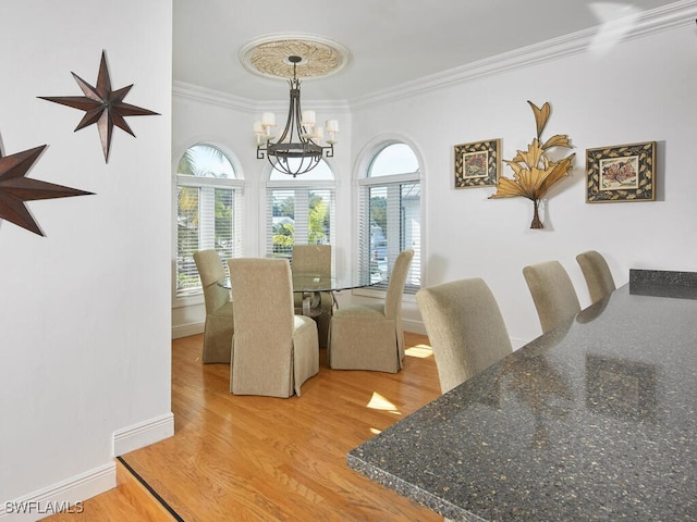 dining area with hardwood / wood-style flooring, ornamental molding, plenty of natural light, and a notable chandelier