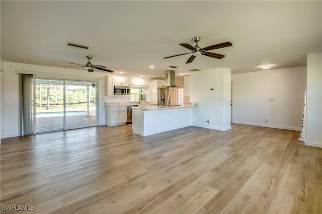 kitchen featuring ceiling fan, appliances with stainless steel finishes, white cabinets, kitchen peninsula, and light wood-type flooring