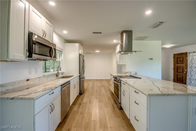 kitchen featuring sink, white cabinetry, light stone counters, island range hood, and appliances with stainless steel finishes