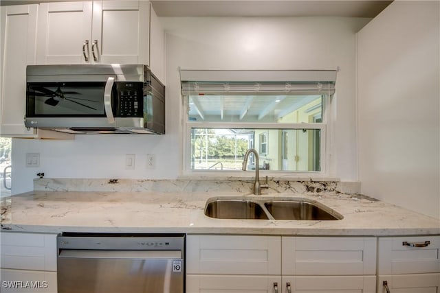 kitchen with white cabinetry, sink, light stone counters, and appliances with stainless steel finishes