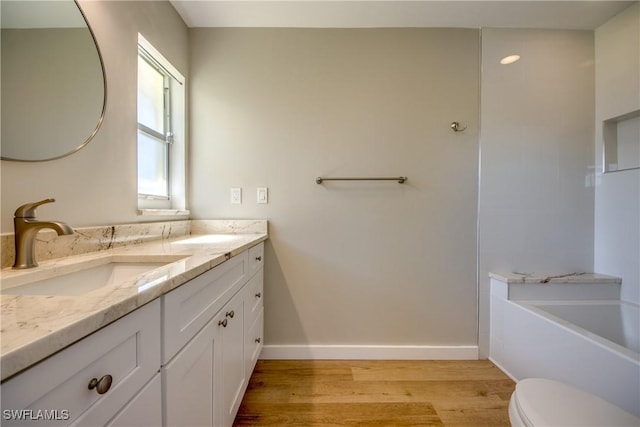 bathroom featuring vanity, hardwood / wood-style flooring, a tub, and toilet