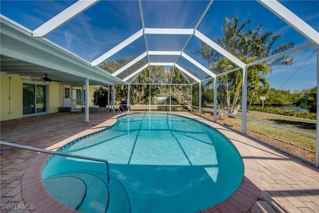 view of swimming pool with ceiling fan, a patio, and glass enclosure