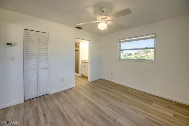 unfurnished bedroom featuring ceiling fan, ensuite bath, light hardwood / wood-style floors, and a closet