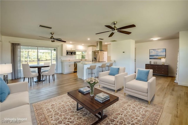 living room with ceiling fan and light hardwood / wood-style flooring