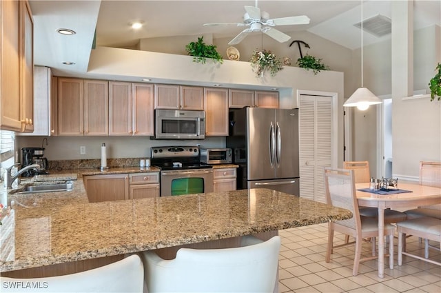 kitchen with appliances with stainless steel finishes, sink, pendant lighting, and a kitchen breakfast bar