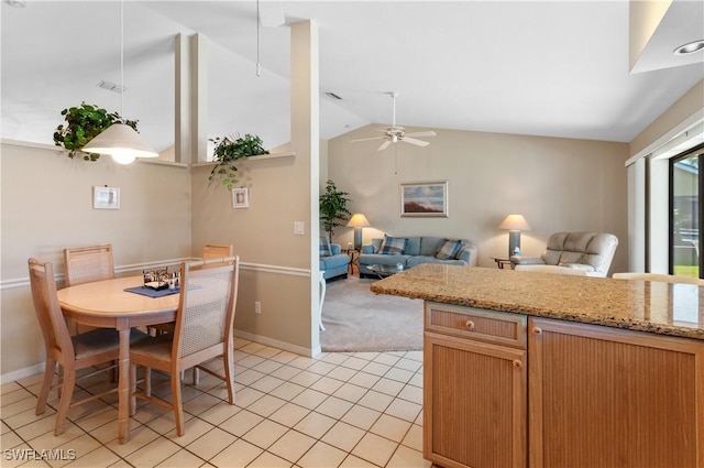 kitchen with ceiling fan, lofted ceiling, light stone countertops, and light tile patterned floors