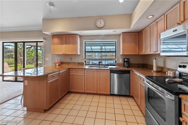 kitchen featuring stone countertops, sink, light tile patterned floors, kitchen peninsula, and stainless steel appliances